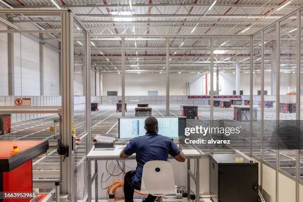 man operating parcel sorting robot system in warehouse - automated guided vehicles stockfoto's en -beelden