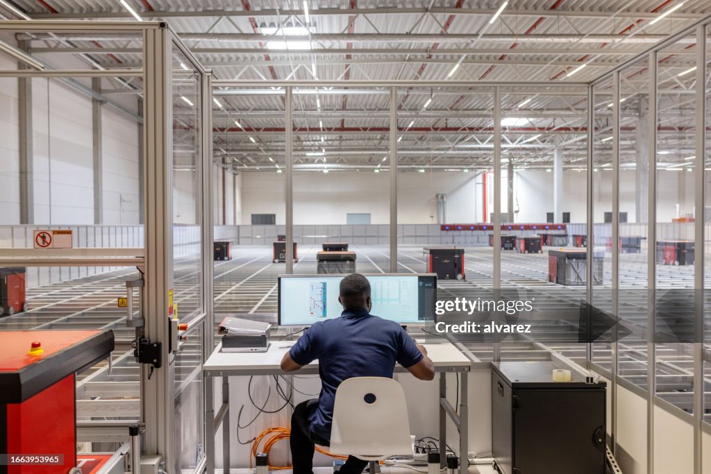 Man operating parcel sorting robot system in warehouse