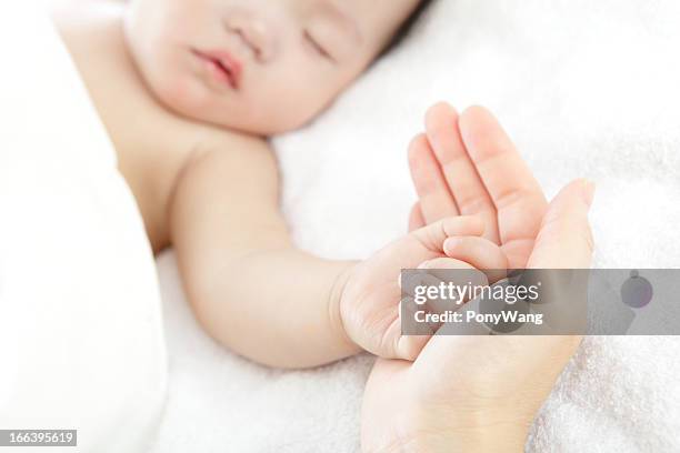 kleines baby mit mutter hand - bed on white background stock-fotos und bilder