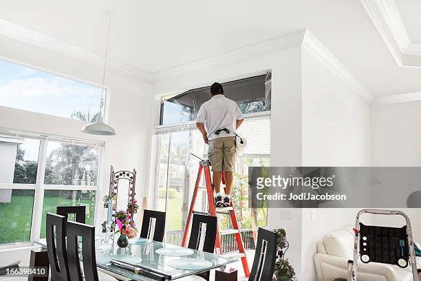 workman on ladder adding tinting to upper, interior window - toned image 個照片及圖片檔