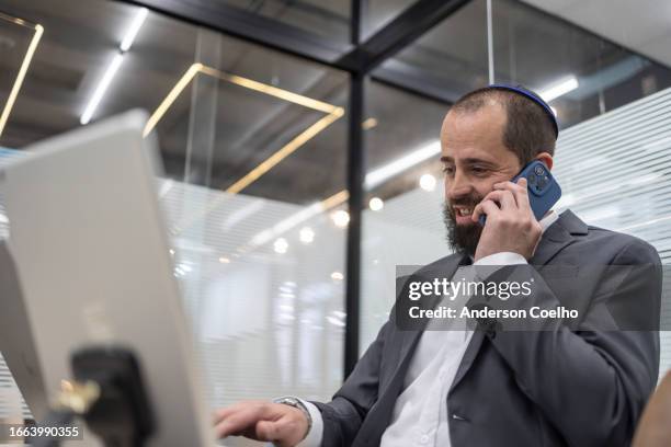 jewish man working in office with notebook and phone - modern judaism stock pictures, royalty-free photos & images