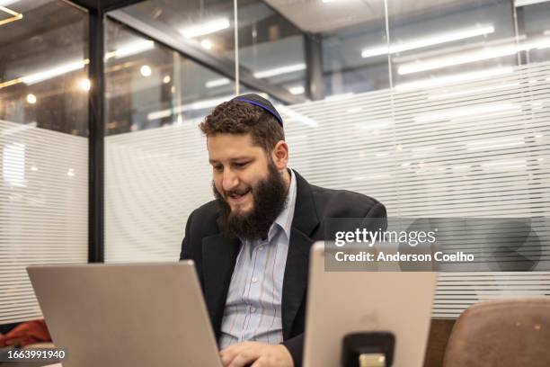 jewish man using laptop in office - judeus imagens e fotografias de stock
