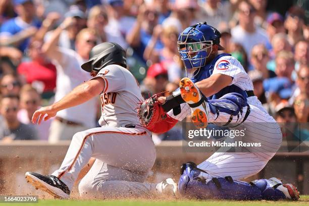 Paul DeJong of the San Francisco Giants is tagged out a home by Miguel Amaya of the Chicago Cubs during the third inning at Wrigley Field on...