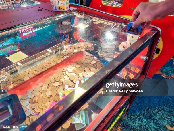 amusement arcade game with hand putting in a coin - tvåpencemynt bildbanksfoton och bilder