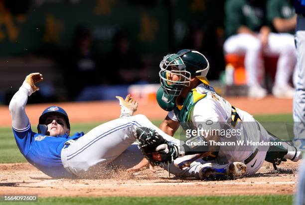 Cavan Biggio of the Toronto Blue Jays scores sliding past catcher Carlos Perez of the Oakland Athletics in the top of the second inning at...
