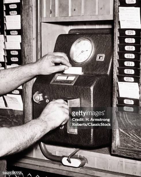 1940s Dirty hands of industrial workman punching out after his shift on factory time clock with his time card.