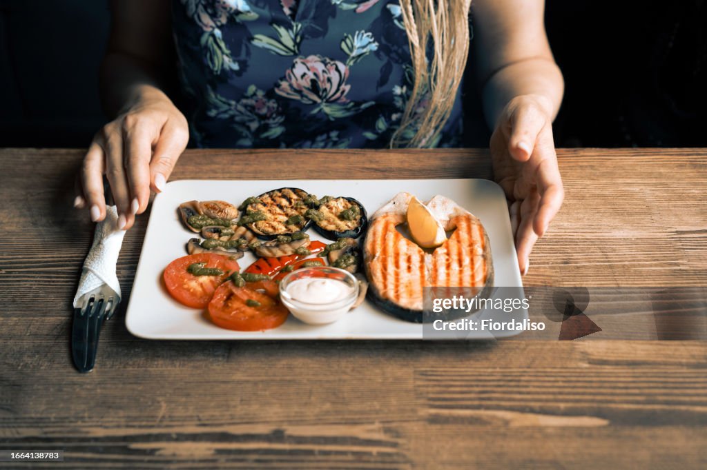 Women eating diet grilled salmon, eggplant, tomatoes