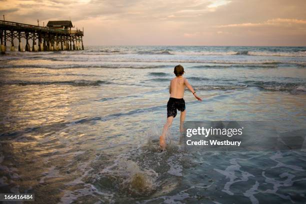 boy running into the water - orlando florida stock pictures, royalty-free photos & images