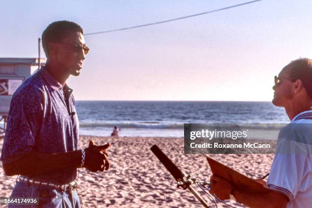 Scottie Pippen of the Chicago Bulls speaks to an interviewer holding a microphone with the sandy beach, a blue lifeguard tower and the Pacific Ocean...