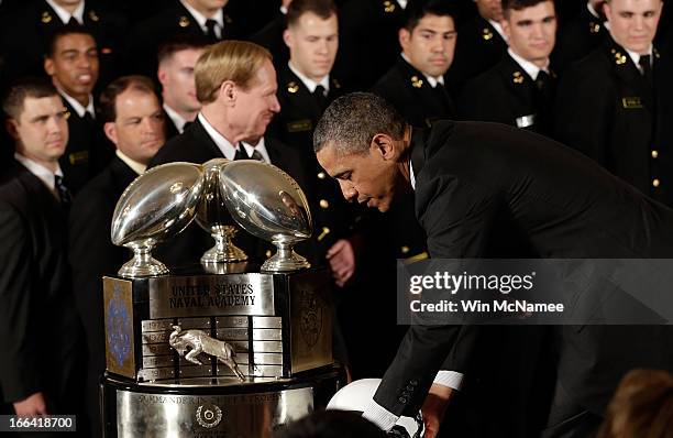 President Barack Obama puts down a Navy football helment given to him after he presented the Commander-in-Chief Trophy to the United States Naval...