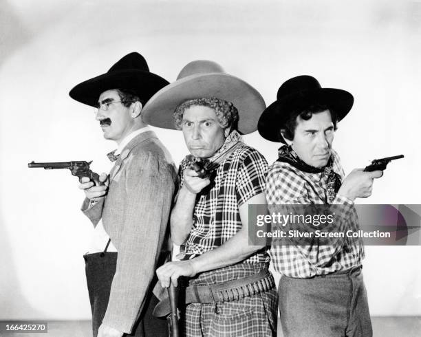 The Marx Brothers Groucho Marx , Harpo Marx and Chico Marx pose holding toy pistols and wearing cowboy outfits, circa 1935.