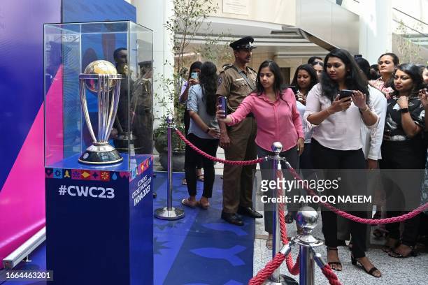 People take pictures of the ICC Men's Cricket World Cup 2023 trophy on display as part of an official trophy tour in Colombo on September 14, 2023.