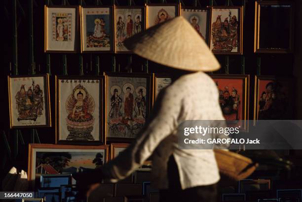 The District Of Cholon In Saigon , Vietnam. Saigon - 1961 - Dans le quartier chinois de Cholon, une personne portant un chapeau conique, dans la...