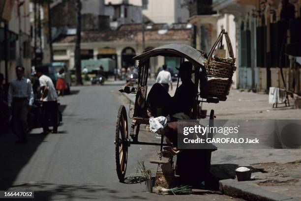 The District Of Cholon In Saigon , Vietnam. Saigon - 1961 - Dans une rue du quartier chinois de Cholon, devant un chariot appelé 'tac-à-tac', dans...