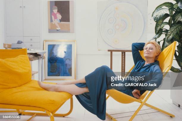 Rendezvous With Michele Morgan. Attitude souriante de Michèle MORGAN en robe longue bleue, assise sur une sorte de chaise longue jaune, les pieds...