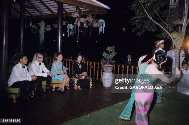 Official Visit Of The Shah Of Iran To Thailand. Bangkok - février 1968 - La nuit, assis sur de petits sièges, sur une terrasse couverte en bois, le...