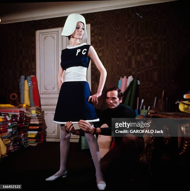 Fashion By Pierre Cardin. Le 22 janvier 1967, dans son atelier, le couturier Pierre CARDIN accroupi derrière un mannequin, ajuste une robe de sa...