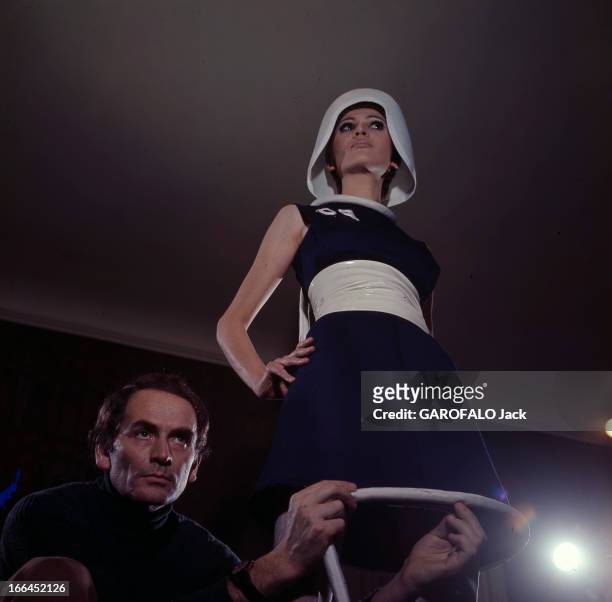Fashion By Pierre Cardin. Le 22 janvier 1967, dans son atelier, le couturier Pierre CARDIN accroupi à côté d'un mannequin, réalise une robe de sa...