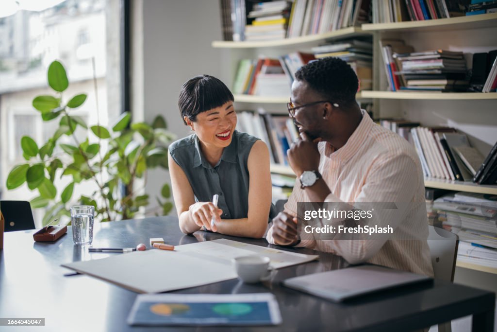 Two Happy Colleagues Talking While Working Together In The Office