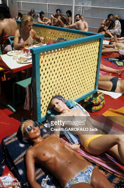 Topless At The Pool Deligny. Paris - mars 1973 - Allongée sur des serviettes au solarium de la piscine Deligny, deux femmes bronzant les seins nus,...