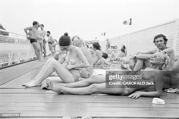 Topless At The Pool Deligny. Paris - mars 1973 - Sur le solarium de la piscine Deligny, jeunes femmes aux seins nus bronzant allongées, première...