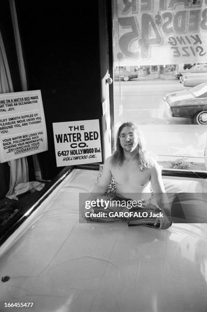 Communities In California. Etats-Unis, Californie, janvier 1971, ici dans un magasin, un homme est assis les jambes croisées sur un 'lit à eau' dont...