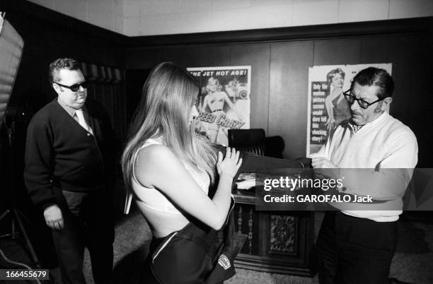 Communities In California. Etats-Unis, Californie, janvier 1971, ici dans les locaux d'une société de production de films, le patron aide une femme...