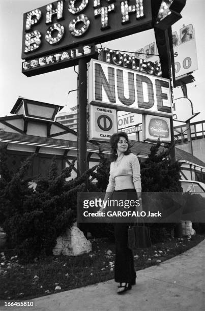 Communities In California. Etats-Unis, Californie, janvier 1971, ici une femme portant un pull court laissant apparaitre son ventre nu marche devant...