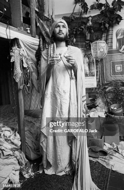 Communities In California. Etats-Unis, Californie, janvier 1971, ici dans un appartement où règne le désordre, un jeune homme barbu s'est enveloppé...