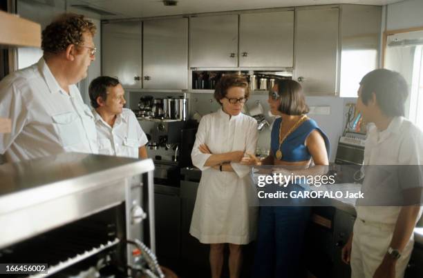 Billionaires Holidays In Monaco. Monaco - août 1974 - Dans la cuisine de son yacht 'La Belle Simone', Simone LEVITT en bleu, une boussole-bijou en...