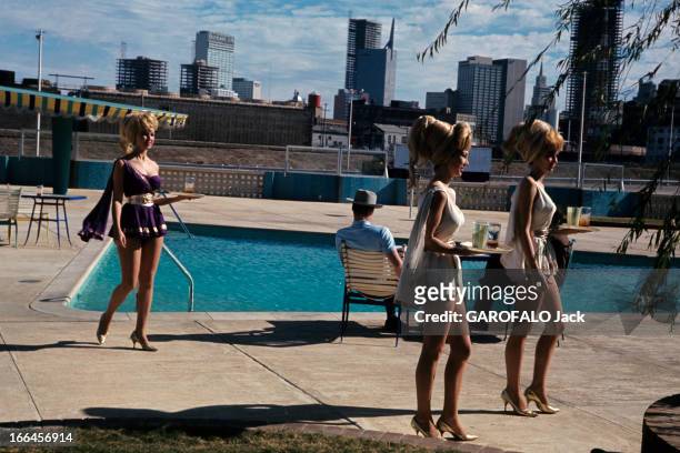Dallas, Texas Capital. Dallas - 1963 - Sur la terrasse au bord de la piscine du motel 'Cabana', trois serveuses portant chacunes des boissons sur un...