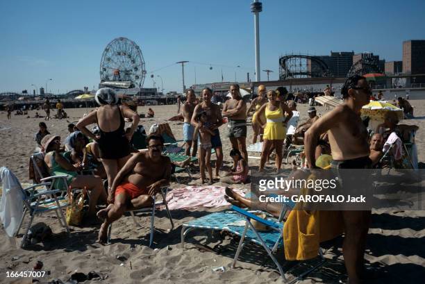 New York, United States. New York - août 1971 - Dans le quartier de Brooklyn, un groupe de personnes sur la plage de Coney Island, devant le parc...
