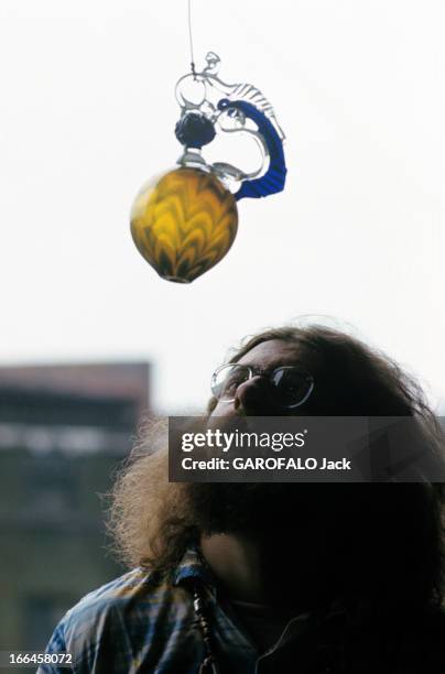 Craftsmans In Usa. Etats Unis- octobre 1972- Artisanat: Portrait d'un souffleur de verre observant une création originale faite d'une sphère colorée,...