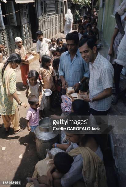 Jesuits In India. En Inde, en mai 1973, dans une rue, le père jésuite Sydney D'SOUZA en chemisette à carreaux, distribuant du pain de mie à des...