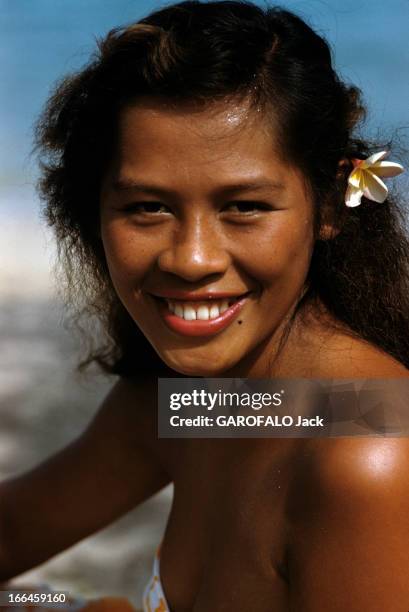 Tahiti In July. Tahiti - juillet 1959 - Portrait d'une femme tahitienne souriante, portant une fleur dans ses cheveux.