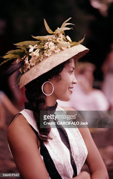 Tahiti In July. Tahiti - juillet 1959 - Portrait d'une femme tahitienne souriante, portant un chapeau orné de fleurs.