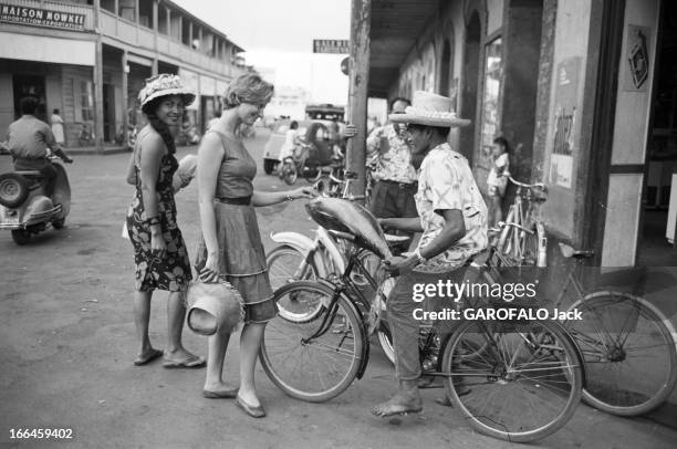 Elles Et Eux ' In Tahiti. En 1961, 'ELLES et EUX' à TAHITI . Dans les rues d'un village, Martine CAROL ? cheveux courts et chapeau à la main discute...