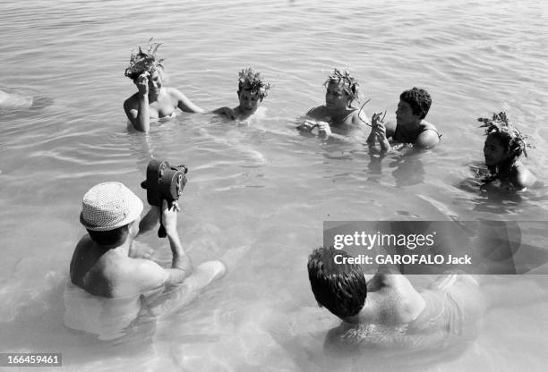 Elles Et Eux ' In Tahiti. En 1961, 'ELLES et EUX' à TAHITI. Assis dans l'eau un homme avec un chapeau filme avec une camera d'autres personnes non...