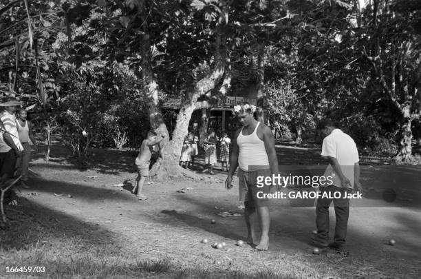 French Polynesia. Le 12 janvier 1959, à Tahiti en Polynésie française, l'ile au quotidien : des hommes dont un avec un chapeau de fleurs, jouent à la...