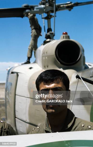 Daily Life In Iran. En Iran, en mai 1975, portrait d'un soldat devant un hélicoptère de l'armée. Un autre soldat se tient debout à côté des pales de...