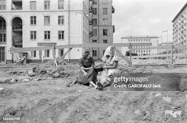 Moscow. Moscou- 31 Juillet 1958- Reportage sur la ville: deux jeunes filles en robe, un fichu noué sur leurs cheveux blonds, assises sur un terrain...