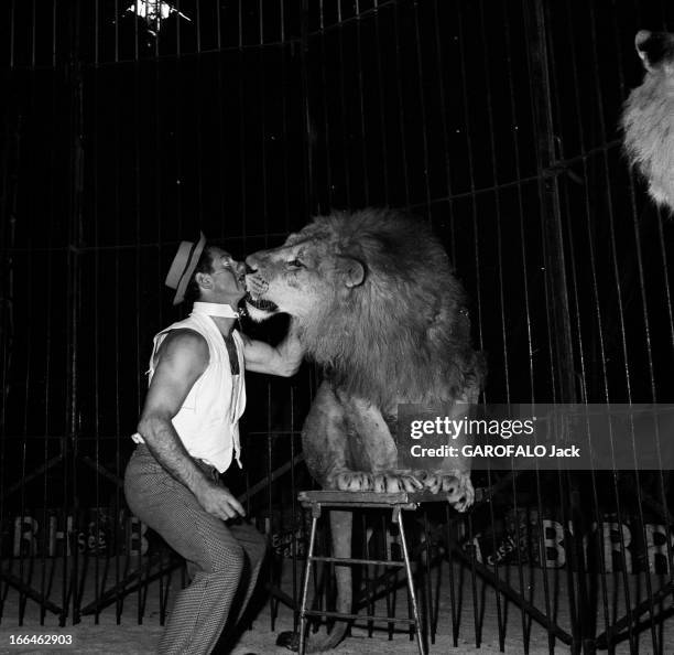 Circus Achille Zavatta. La troupe d'Achille ZAVATTA lors d'une tournée : ici déguisé en clown, dans une cage, embrasse un des deux lions assis sur...