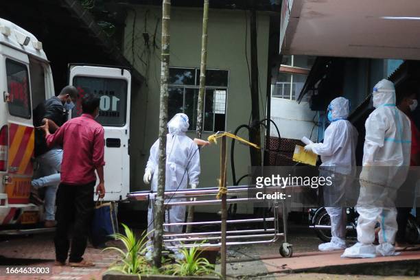 Health workers wearing protective gear shift people who have been in contact with a person infected with the Nipah virus to an isolation center at a...