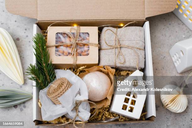 christmas gift basket with wax candle, ceramic house, paper box with candy, cozy socks and bath bomb. corporate or personal presents. - gift basket stock pictures, royalty-free photos & images