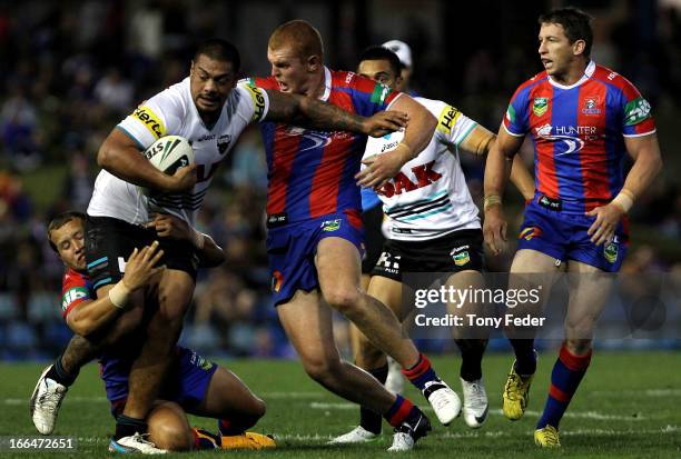 Sika Manu of the Panthers is tackled by Alex McKinnon and Tyrone Roberts of the Knights during the round six NRL match between the Newcastle Knights...