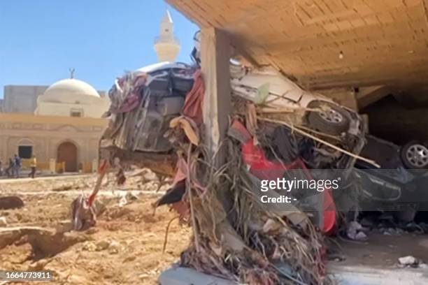 This image grab from AFPTV footage on September 13 shows a view of a destroyed vehicle crashed into a building in the wake of floods after the...