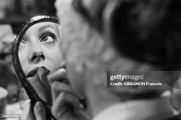 Shooting Of The Film 'Manon 70' By Jean Aurel. Catherine DENEUVE de dos, un bandeau autour de la tête, se mettant du rouge à lèvres entre deux plans...