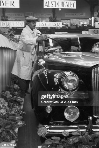 Motor Show In Paris 1954. Paris - octobre 1954 - Au Grand Palais, à l'occasion du 41ème Salon de l'Automobile de Paris, un homme portant une blouse...