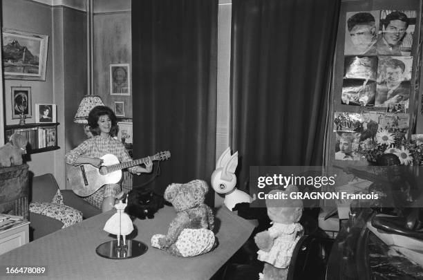 Rendezvous With Sheila. Attitude souriante de SHEILA en pyjama, jouant de la guitare pour ses peluches dans la salle à manger du modeste trois-pièces...