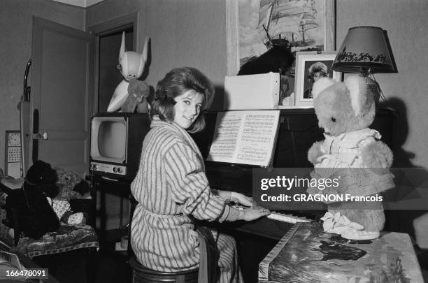 Rendezvous With Sheila. Attitude souriante de SHEILA en robe de chambre, jouant du piano dans la salle à manger du modeste trois-pièces de la Porte...